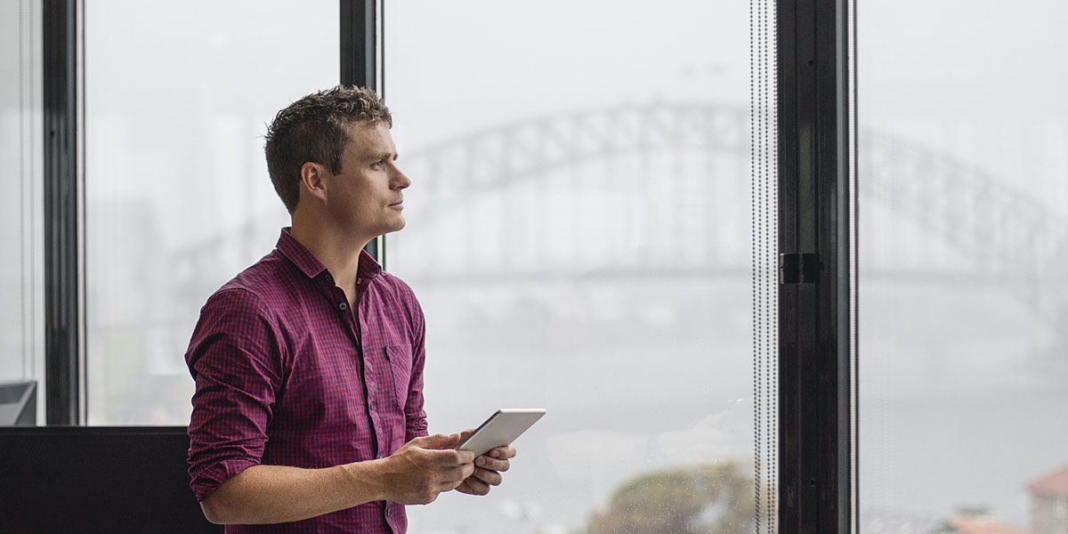 worker standing and holding a tablet while looking out a window