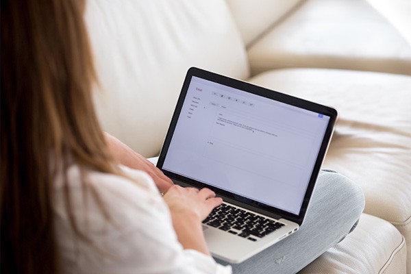 View over a person's shoulder as they type on a laptop.