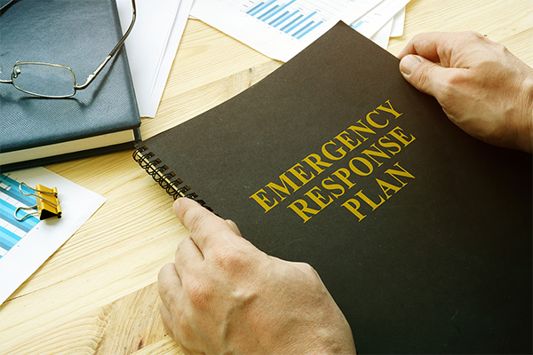 hands holding a book titled emergency response plan